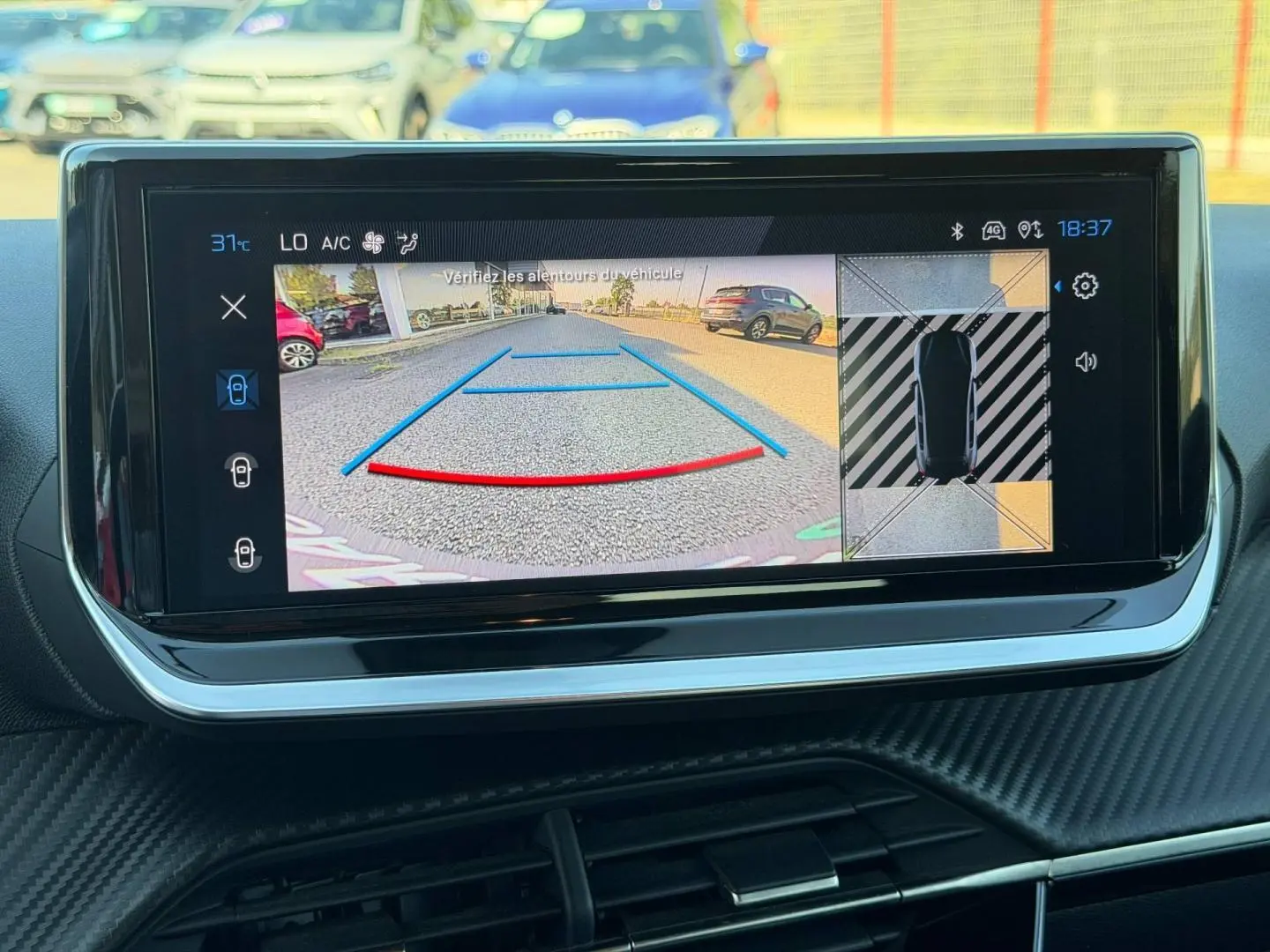 Écran tactile intérieur montrant la caméra de recul et l'aide au stationnement de la Peugeot 208 gris Artense.