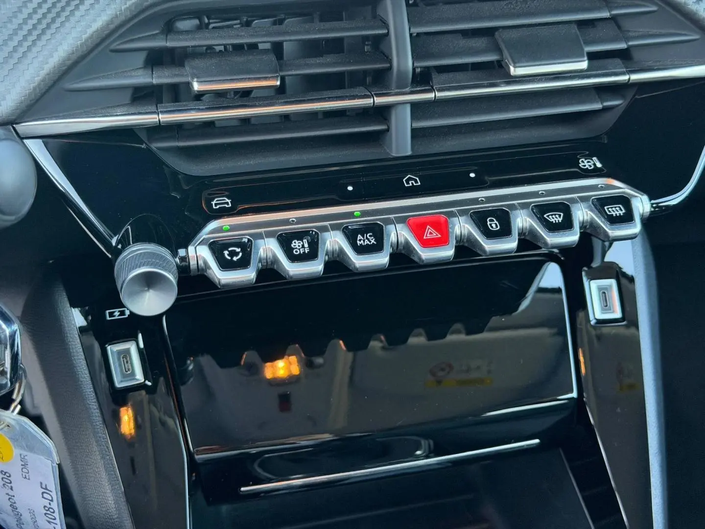 Vue rapprochée de la console centrale de la Peugeot 208 1.2 100ch Allure, boutons argentés et écran tactile noir.