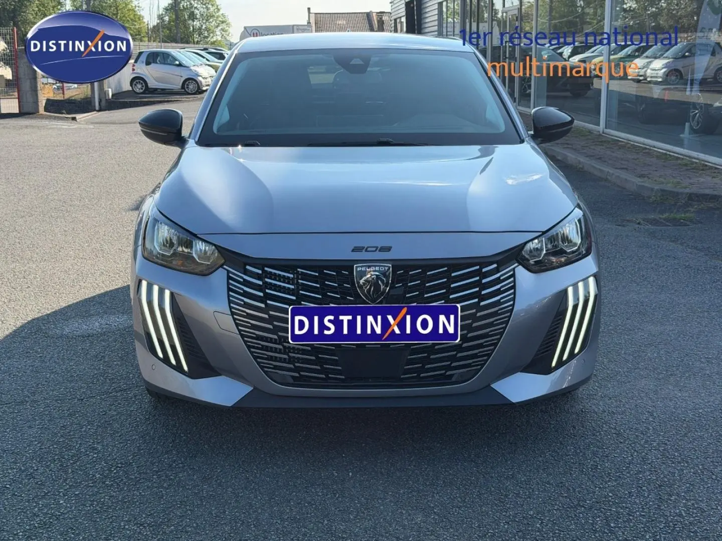 Vue avant frontale de la Peugeot 208 1.2 100ch gris Artense avec feux LED verticaux distinctifs et calandre noire.