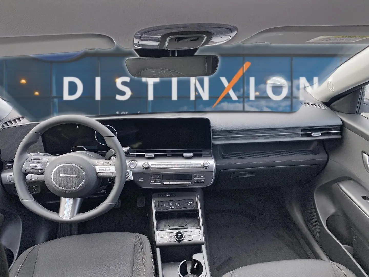 Vue intérieure avant du Hyundai Kona 2025 gris, tableau de bord moderne avec écran large et volant multifonction cuir.