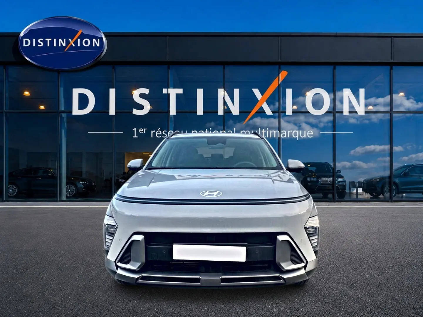 Vue avant d'un Hyundai Kona gris 2025 avec calandre moderne et logo Hyundai visible, devant une vitrine Distinxion.