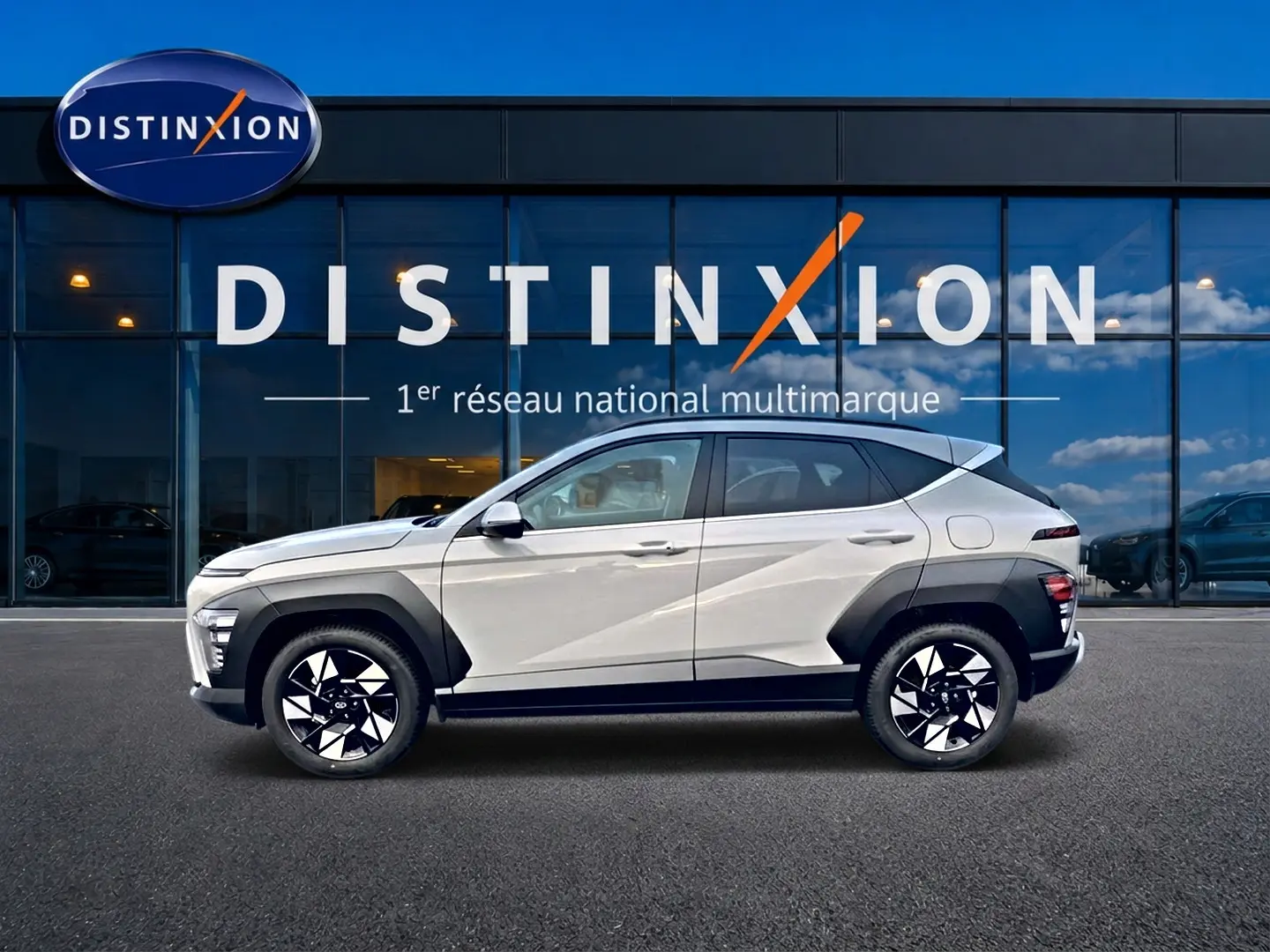 Vue de profil côté gauche d’un Hyundai Kona gris 2025 avec protections noires et jantes alliage bicolores devant un bâtiment Distinxion.