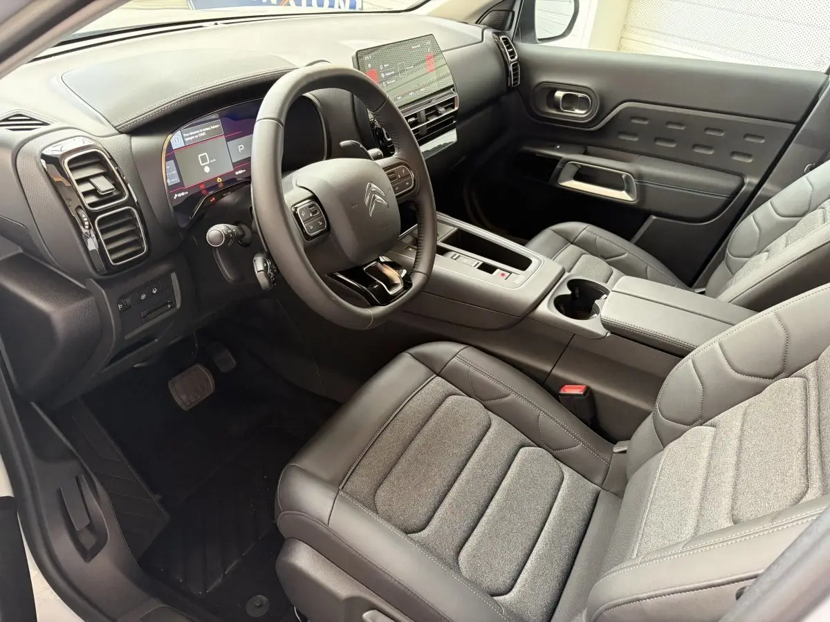 Vue intérieure côté conducteur du Citroën C5 Aircross 2025, sièges gris et tableau de bord avec écran tactile.