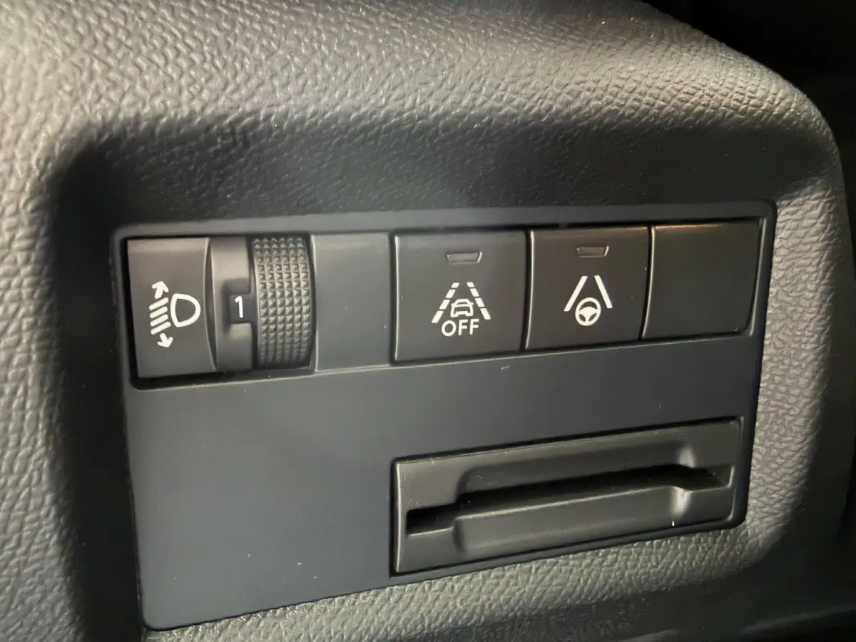 Gros plan sur les commandes noires du tableau de bord du Citroën C5 Aircross 2025, avec réglage phares et aides à la conduite.