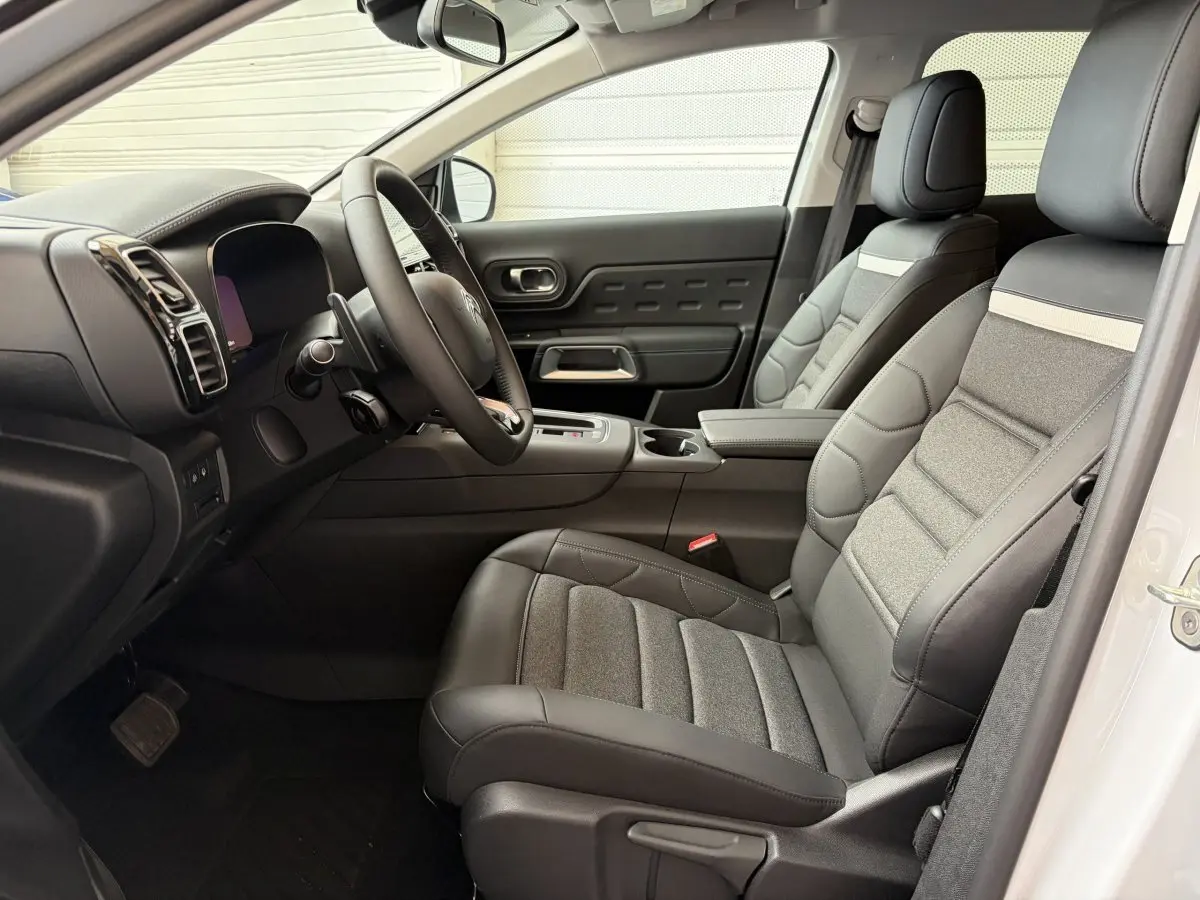 Intérieur avant droit du Citroën C5 Aircross blanc 2025, sièges cuir et tissu gris, tableau de bord moderne avec écran tactile.