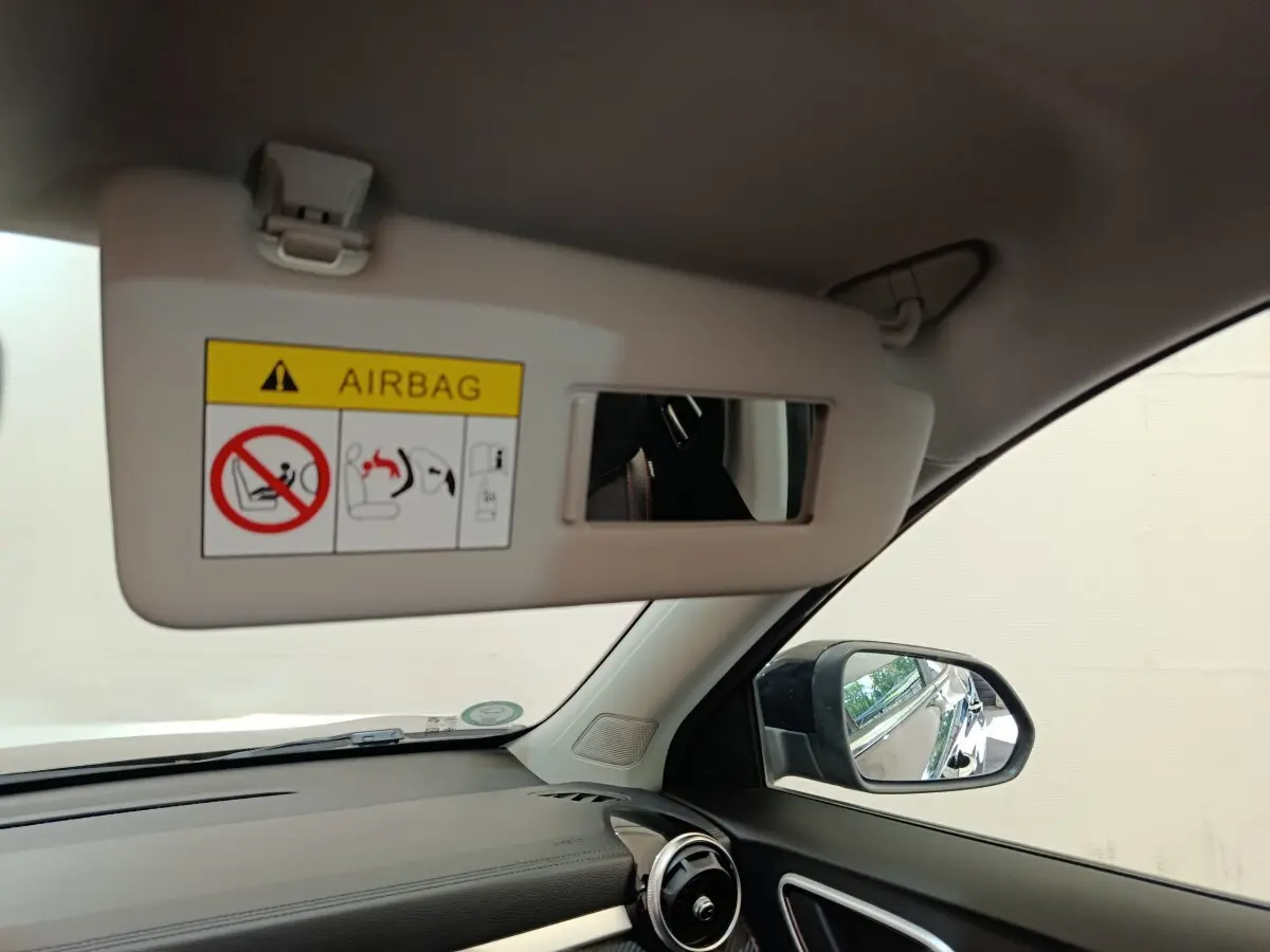 Intérieur MG Motor ZS Luxury 2024 vu côté conducteur, pare-soleil ouvert avec miroir et rétroviseur noir visible.