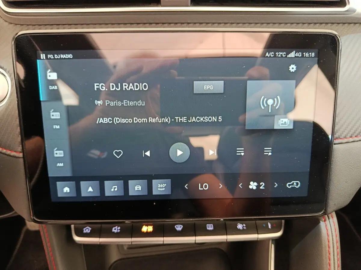 Écran tactile central du MG ZS Luxury 2024 affichant la radio et commandes climatisation, intérieur noir avec surpiqûres rouges.