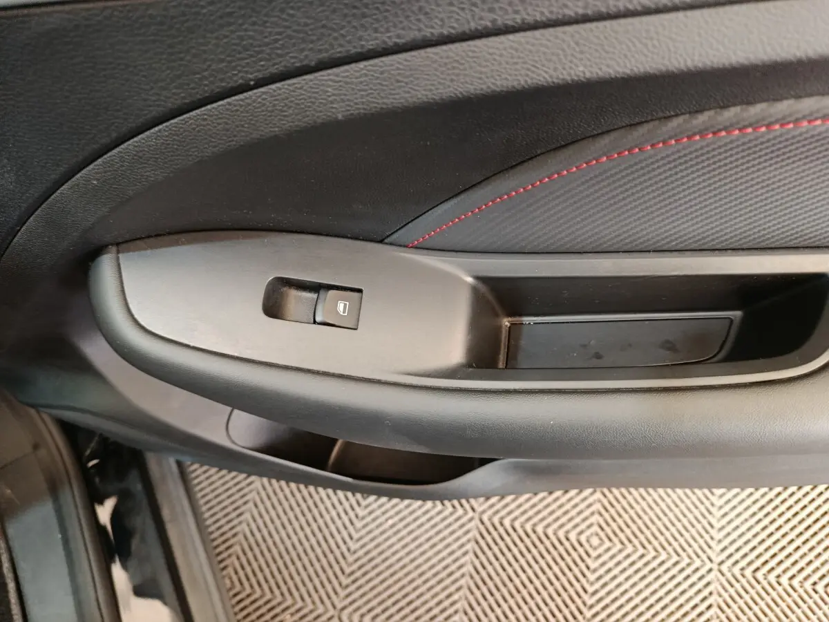 Gros plan sur la poignée intérieure côté conducteur du MG ZS Luxury noir 2024 avec bouton de commande de vitre.