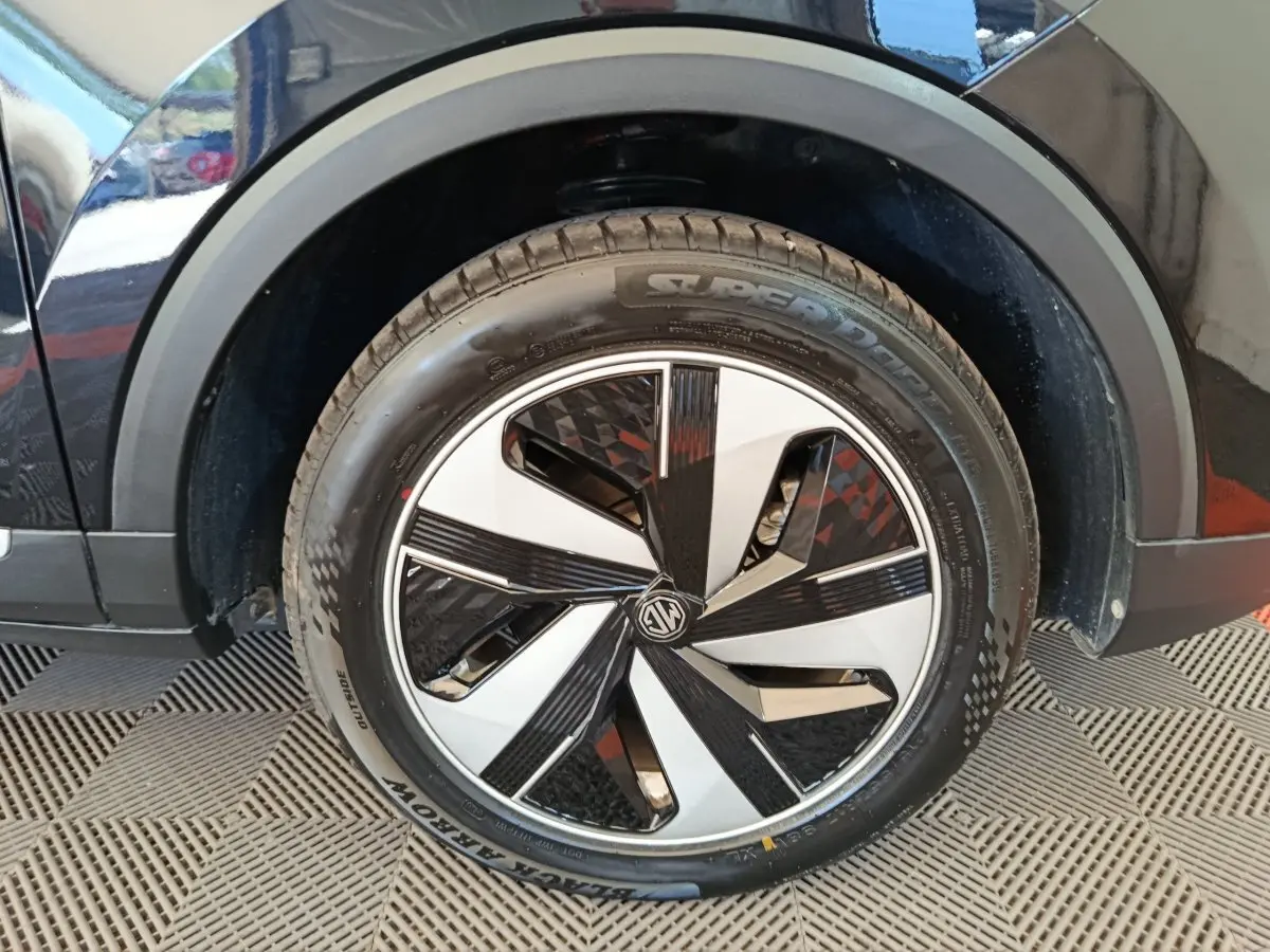Gros plan sur la roue avant droite noire du MG ZS Luxury 70kWh 2024 avec jante au design géométrique bicolore.