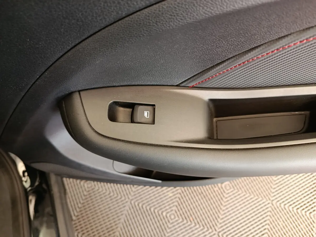 Détail de la commande de lève-vitre sur la porte intérieure côté conducteur du MG Motor ZS Luxury noir 2024.