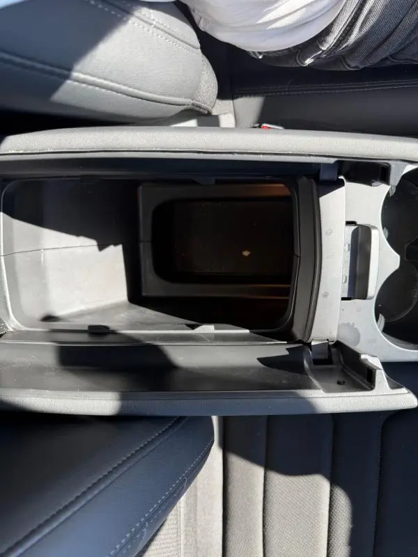 Vue plongeante sur la console centrale noire ouverte du Citroën C5 Aircross hybride 2024, montrant le rangement intérieur.