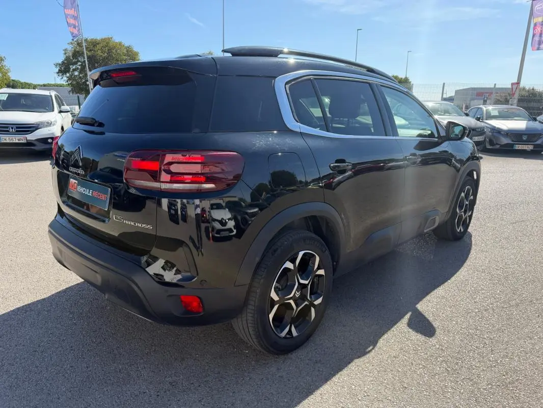 Vue 3/4 arrière droite d'un Citroën C5 Aircross hybride noir 2024 avec jantes distinctives et vitres teintées.