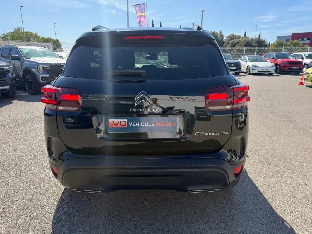 Vue arrière d’un Citroën C5 Aircross noir 2024 avec feux arrière allumés sur un parking extérieur.