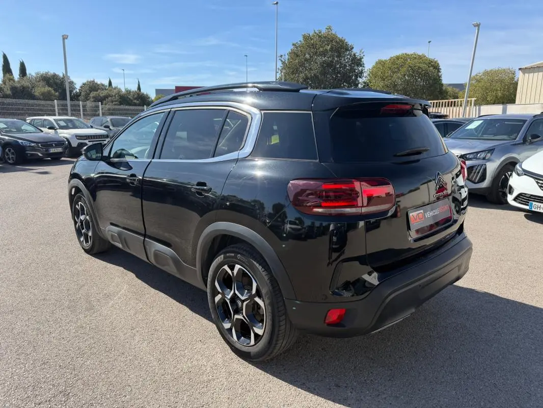 Vue 3/4 arrière droite d'un Citroën C5 Aircross hybride noir 2024 avec jantes distinctives et vitres teintées.
