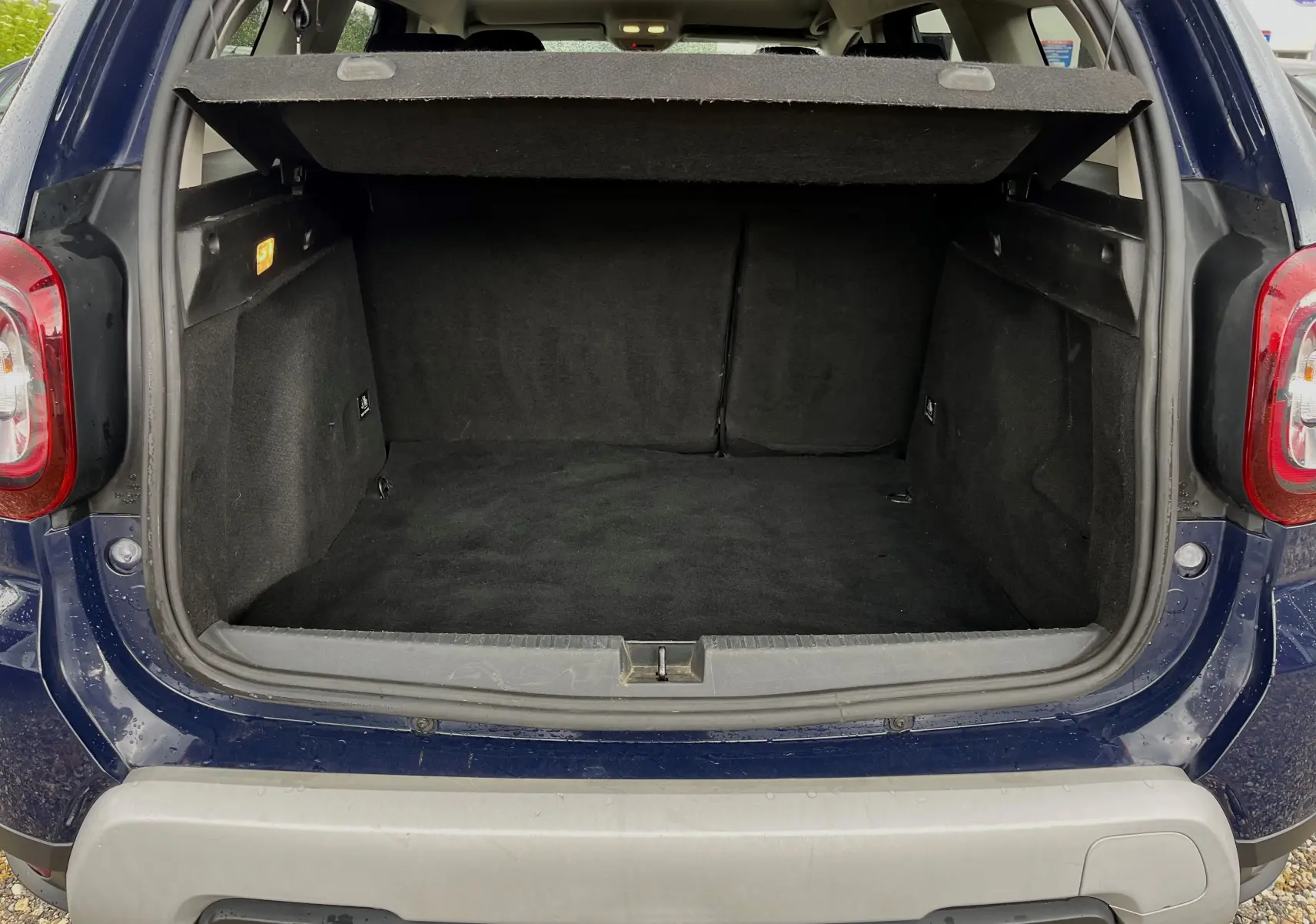 Coffre ouvert d'un Dacia Duster bleu marine 2018 vu de l'arrière, montrant un espace de chargement vide et propre.