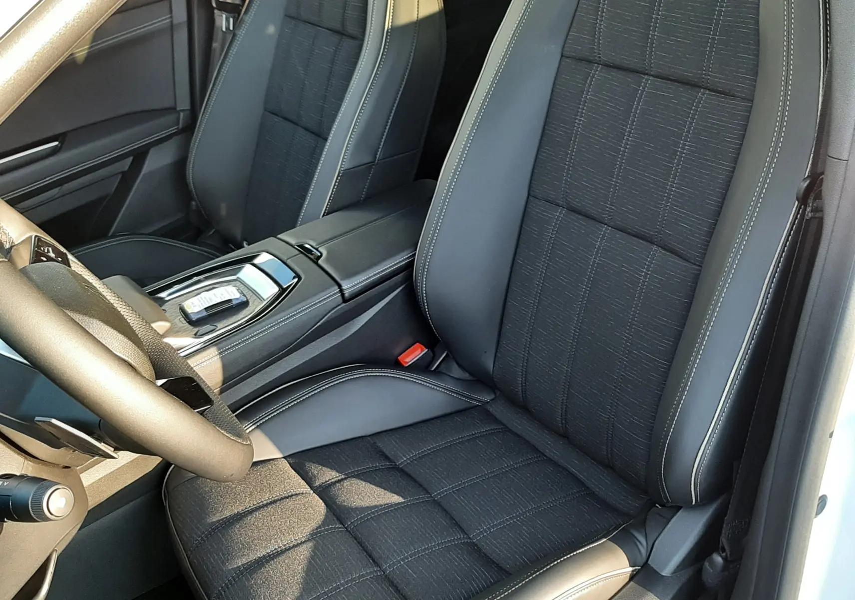 Vue intérieure côté conducteur du Renault Austral E-Tech 2025, sièges noirs en tissu et cuir avec surpiqûres claires.
