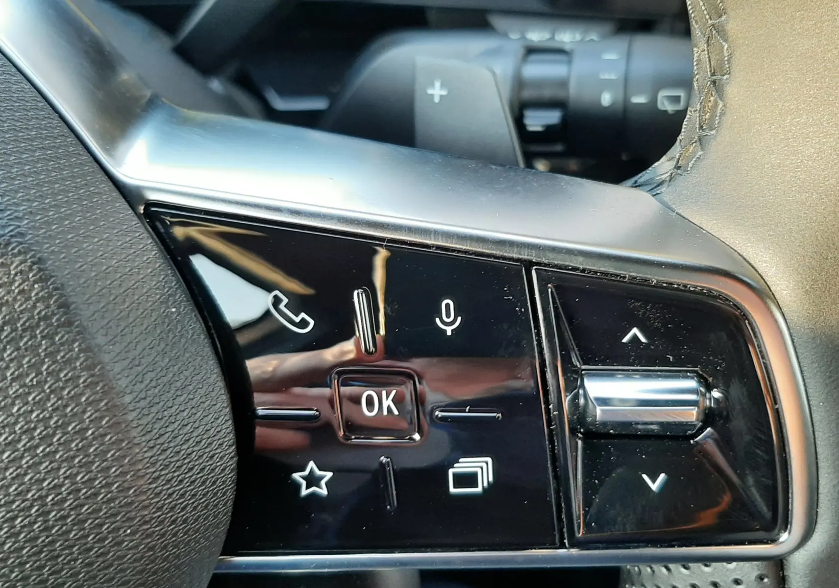 Gros plan sur les commandes multifonctions noires à gauche du volant cuir perforé du Renault Austral E-Tech blanc nacré 2025.