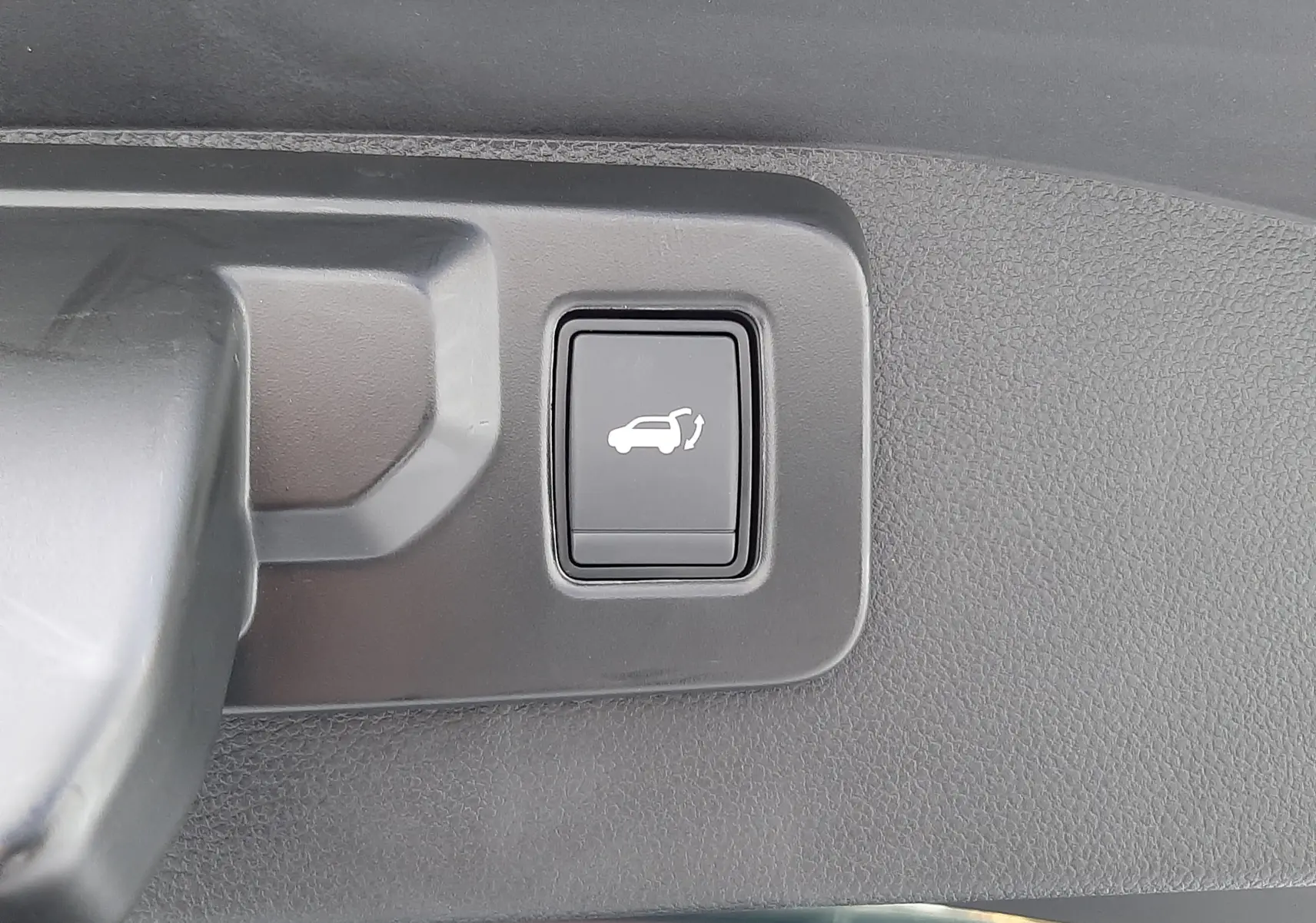 Bouton d'ouverture électrique du hayon sur le coffre intérieur d'un Renault Austral blanc nacré toit noir 2025.