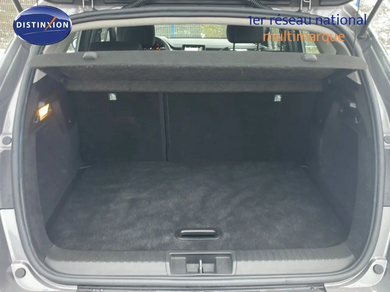 Coffre ouvert vu de l'arrière du Renault Captur gris Cassiopée Métal, espace de chargement vide et propre.