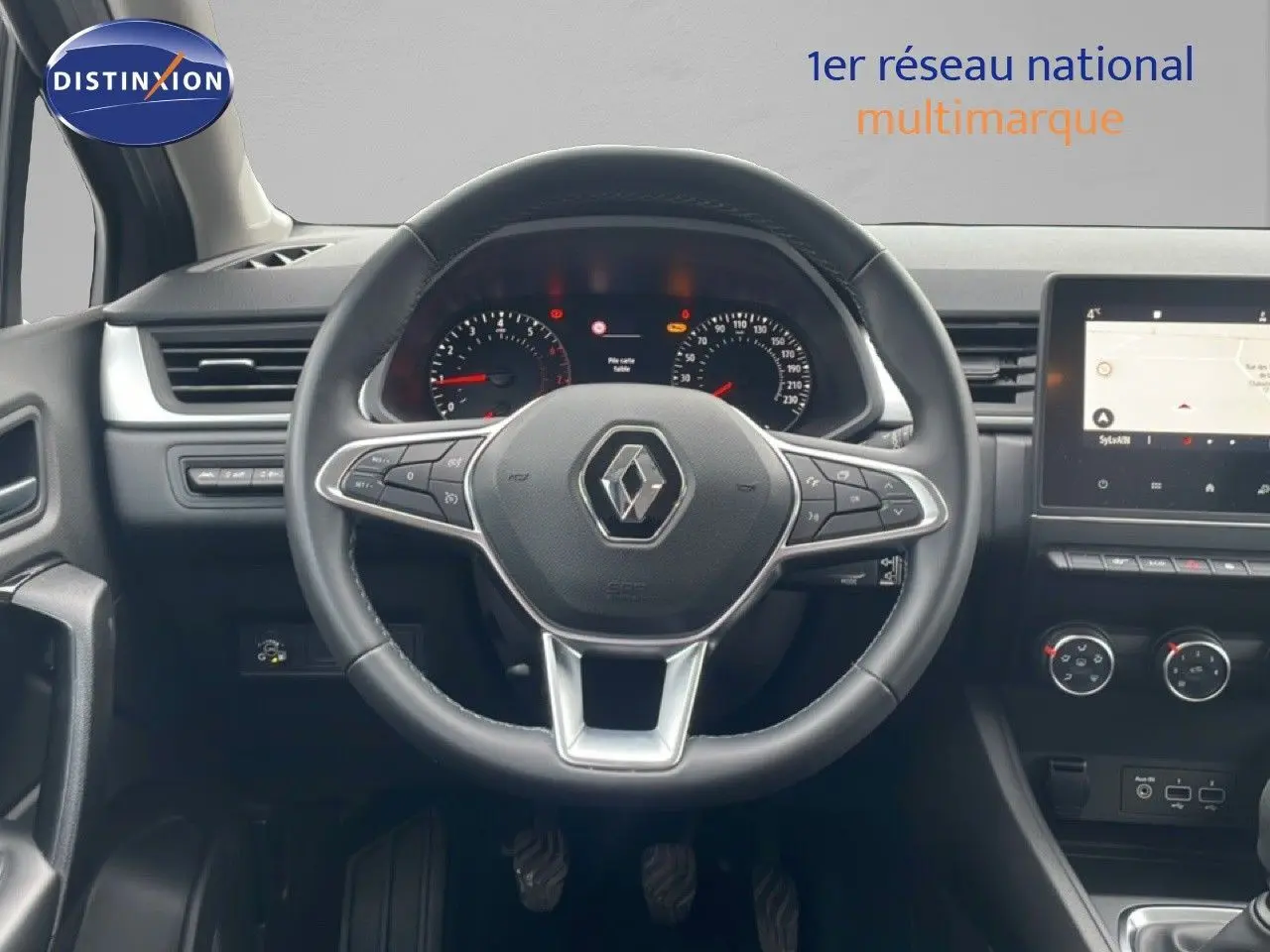 Vue intérieure centrée sur le volant Renault Captur gris cassiopée, tableau de bord et écran tactile en arrière-plan.
