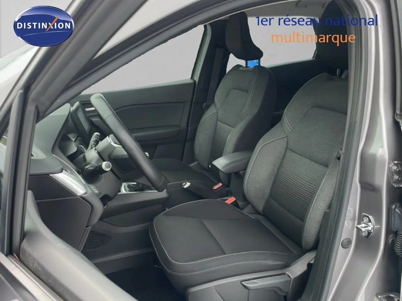 Vue intérieure côté conducteur du Renault Captur gris cassiopée métal, montrant les sièges tissu et le volant multifonction.