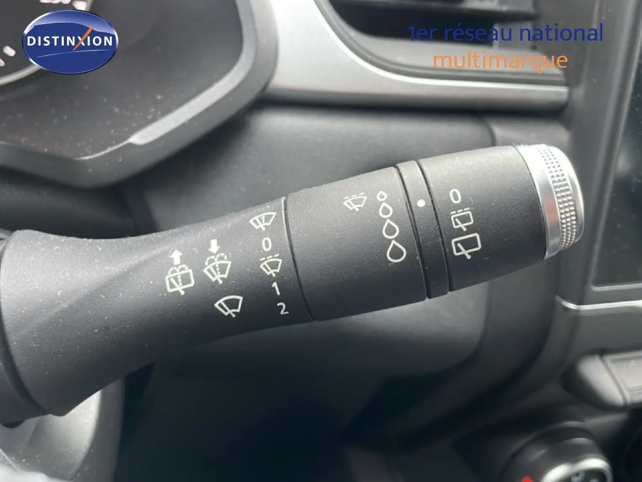 Gros plan sur la commande d’essuie-glace du Renault Captur gris Cassiopée, montrant les réglages et symboles blancs.
