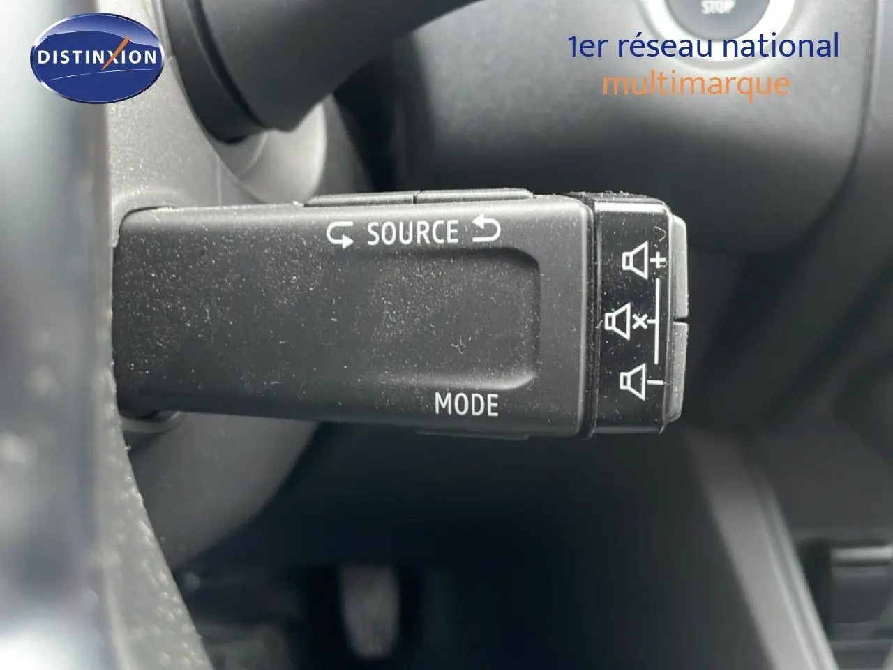 Gros plan sur la commande au volant du Renault Captur gris cassiopée métal, mettant en valeur les boutons source et mode.