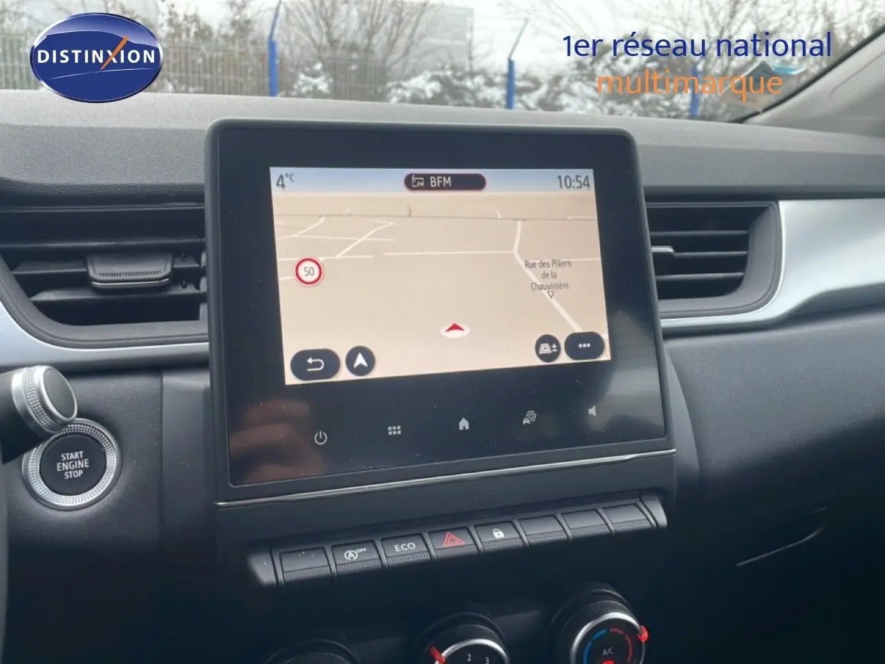 Vue intérieure centrée sur l'écran tactile du tableau de bord du Renault Captur gris Cassiopée, avec commandes climatisation visibles.
