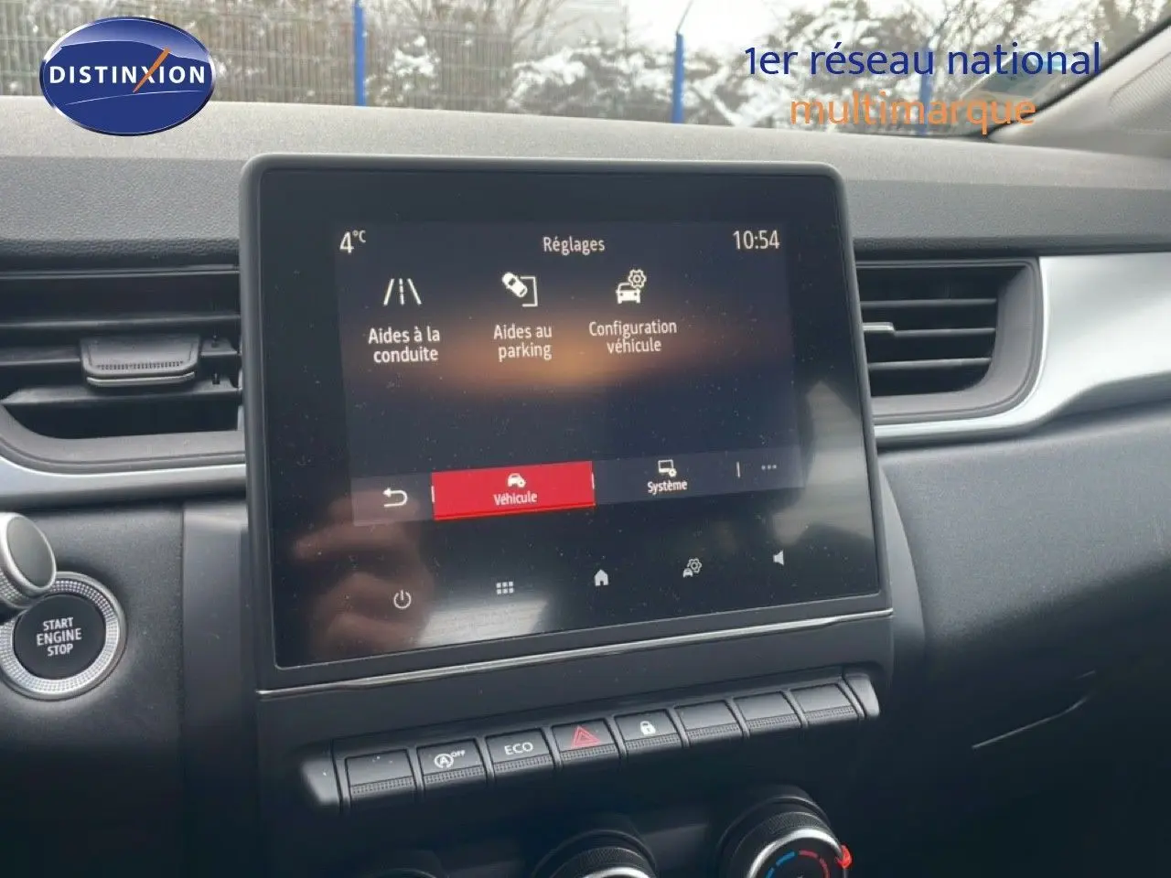 Vue intérieure centrée sur l'écran tactile du tableau de bord du Renault Captur gris Cassiopée, avec commandes et bouton Start visible.