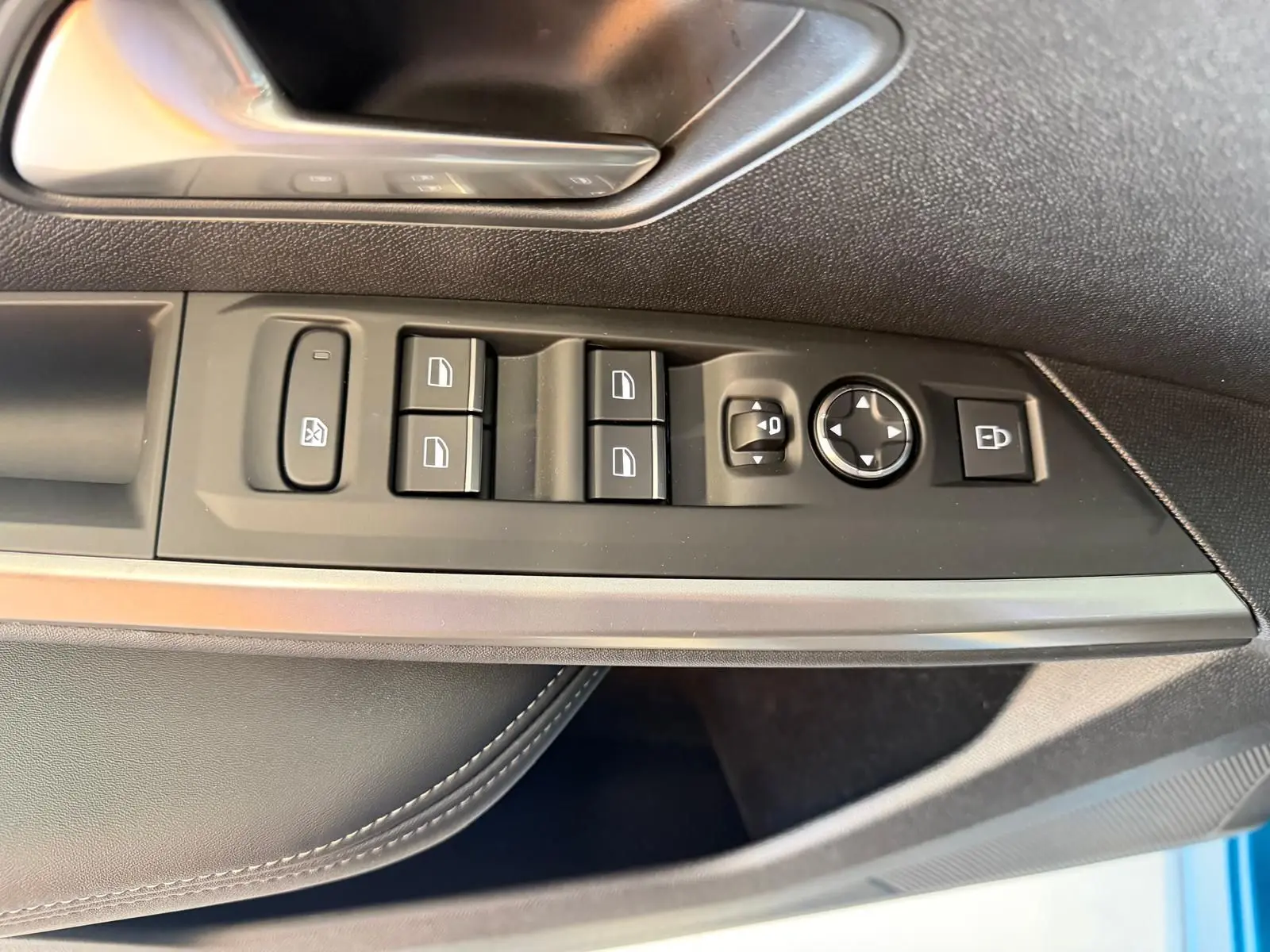 Vue rapprochée des commandes de porte côté conducteur du Peugeot 5008 Hybrid 2025 bleu obsession avec surpiqûres Iced Clay.