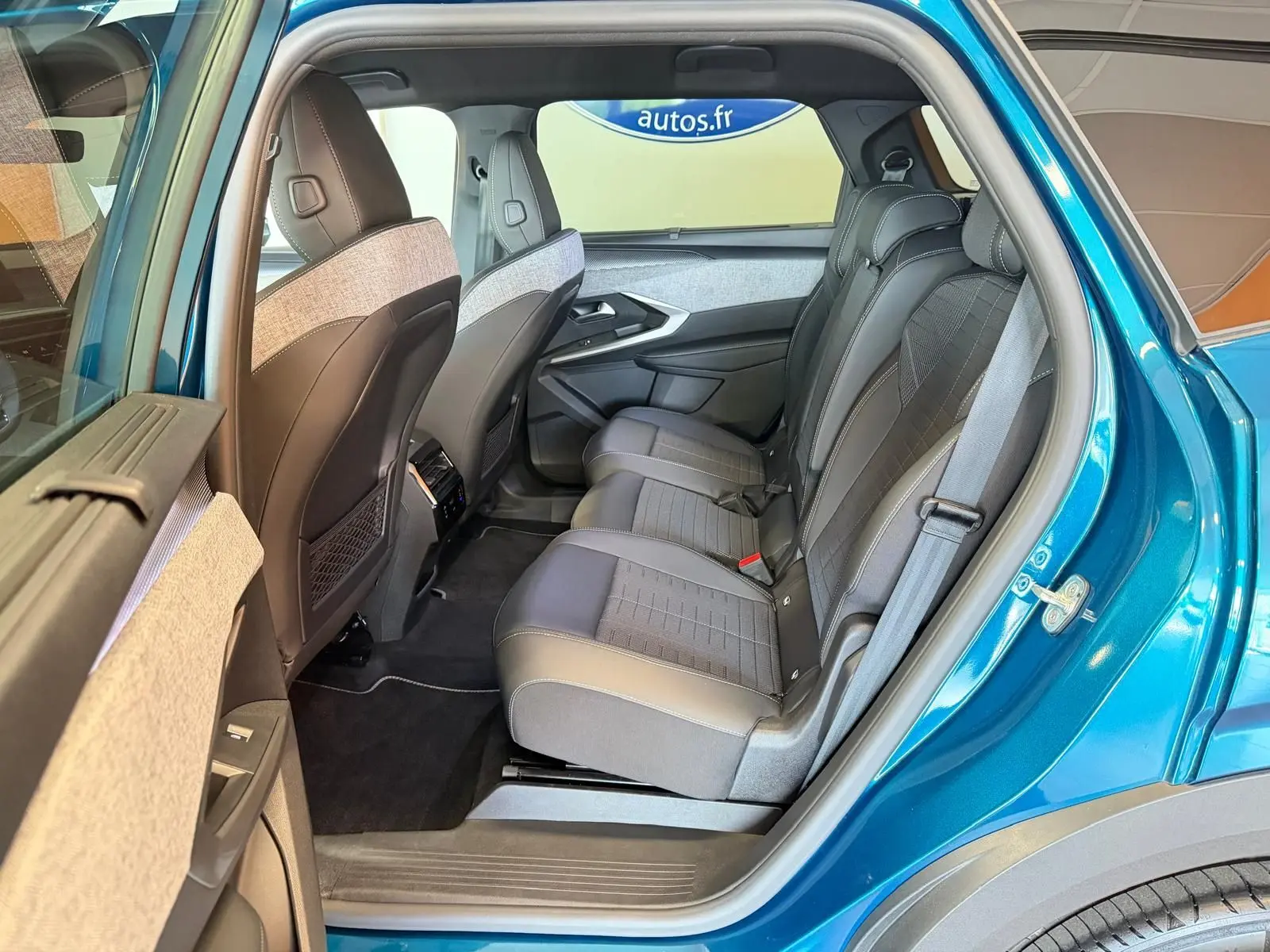Vue côté gauche arrière sur l’intérieur du Peugeot 5008 Hybrid 145 GT bleu Obsession, sièges tissu/tepp noir et gris.