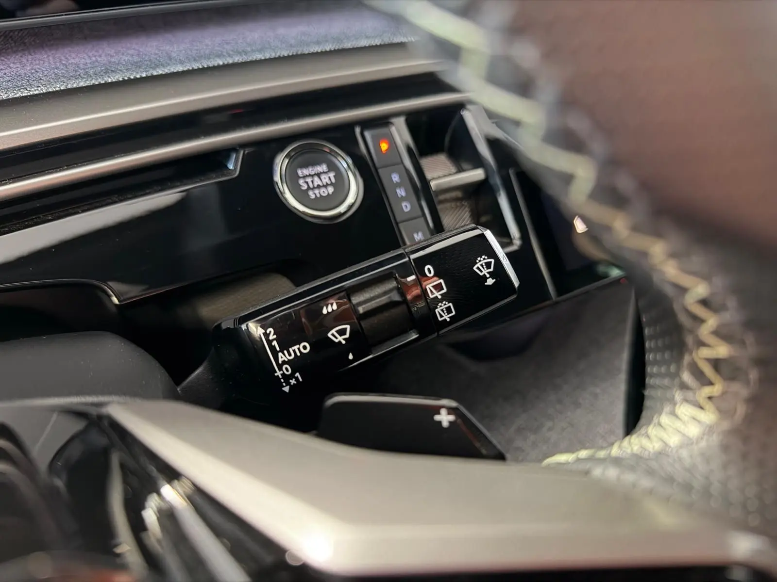 Détail intérieur du Peugeot 5008 Hybrid 145 GT montrant la commande d’essuie-glace et le bouton start/stop, avec surpiqûres jaunes visibles.