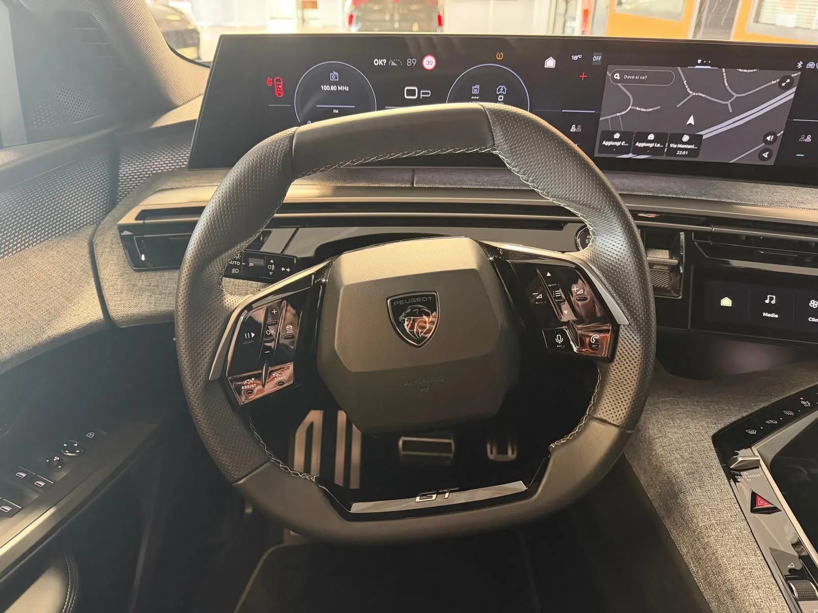 Vue intérieure centrée sur le volant GT du Peugeot 5008 Hybrid 145, avec tableau de bord numérique et écran GPS panoramique.
