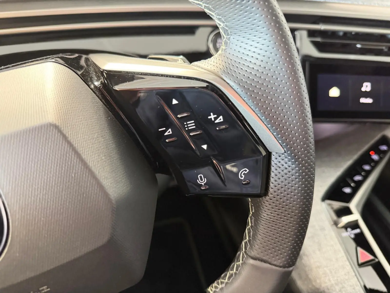 Gros plan sur le volant perforé côté gauche du Peugeot 5008 Hybrid 145 GT, avec commandes vocales et téléphone.