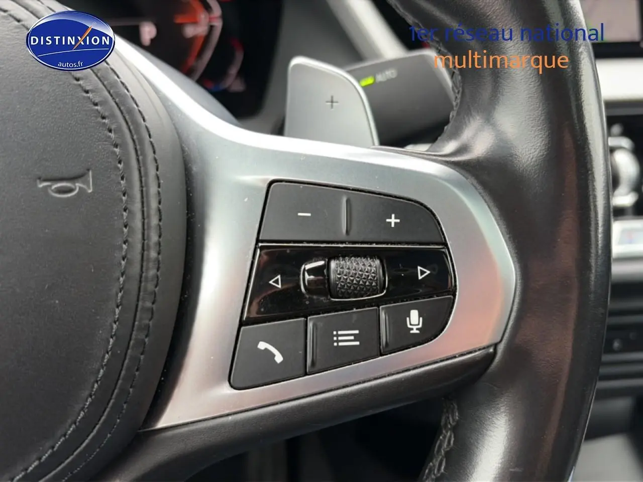 Gros plan sur les commandes multifonctions en métal brossé du volant cuir noir d’une BMW Série 2 Gran Coupe F44.