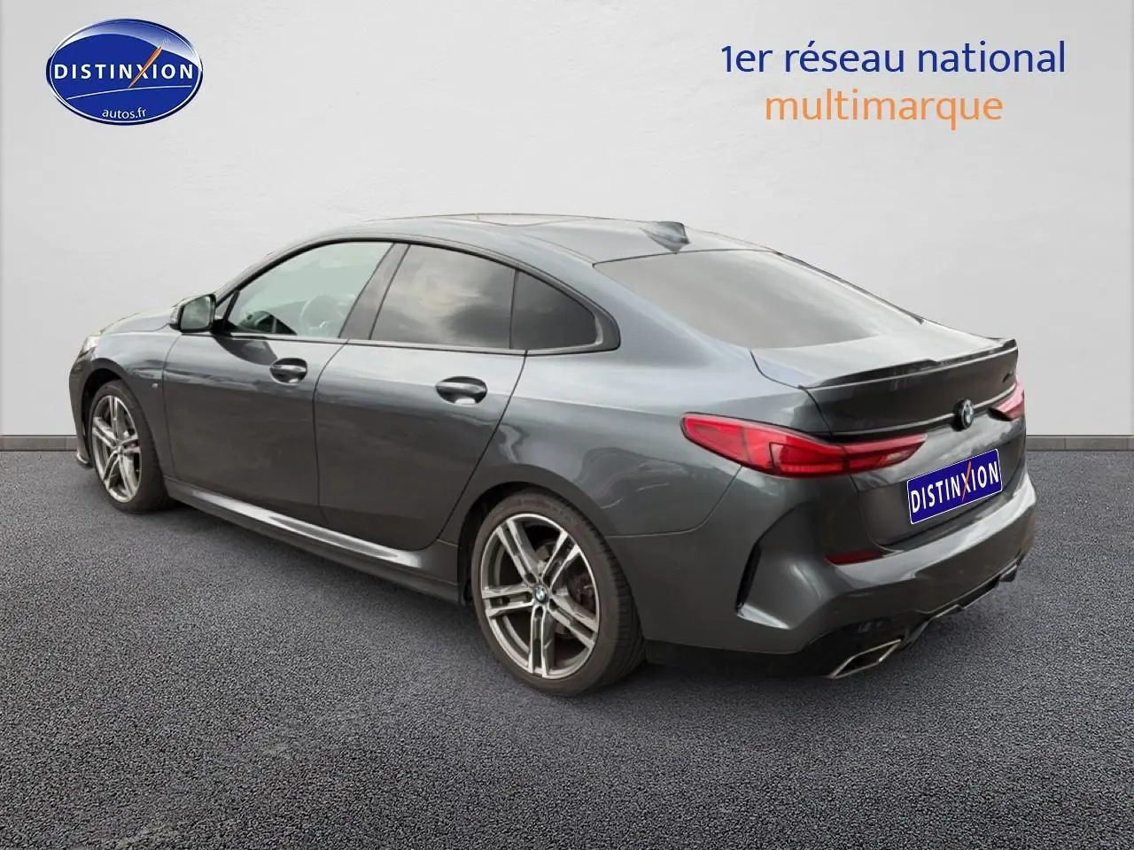 BMW Série 2 Gran Coupé gris vue 3/4 arrière droit, jantes alu et double sortie d’échappement chromée.