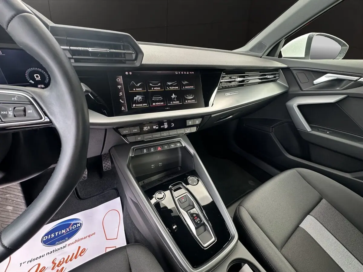 Vue intérieure côté conducteur de l’Audi A3 2024 blanche, mettant en valeur la console centrale moderne et l’écran tactile.