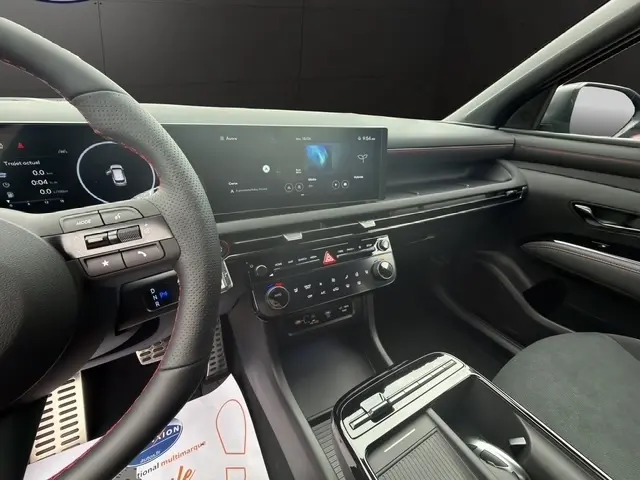 Intérieur avant droit du Hyundai Tucson gris foncé 2026, avec tableau de bord numérique et écran tactile large.