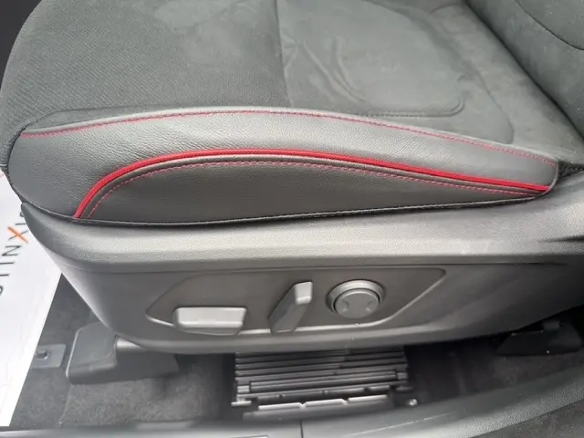 Gros plan sur le côté gauche du siège avant gris foncé avec surpiqûres rouges du Hyundai Tucson 1.6 Hybrid 239 N Line Creative.