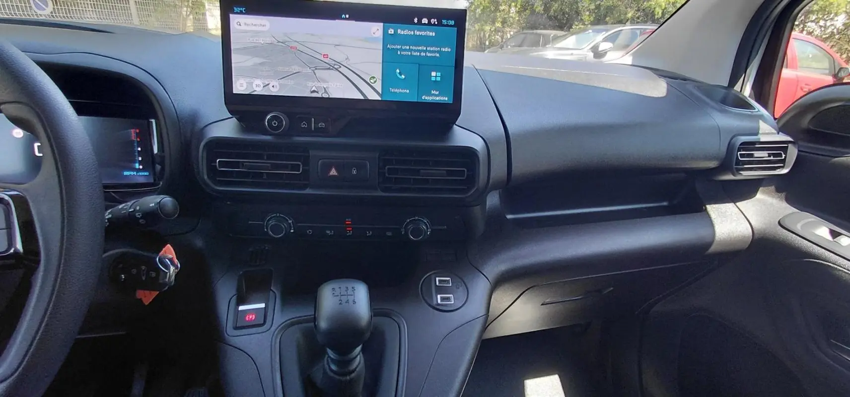 Vue intérieure du tableau de bord du Citroën Berlingo 2025, avec écran tactile et levier de vitesses manuel.