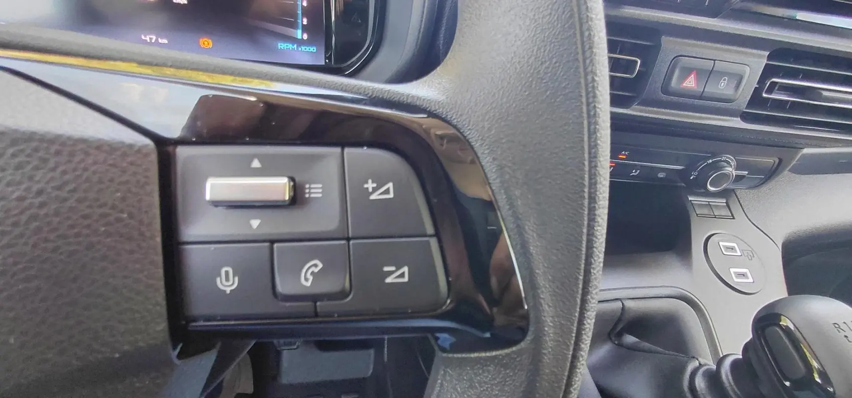 Gros plan sur les commandes du volant multifonctions d’un Citroën Berlingo blanc 2025, version essence manuelle.