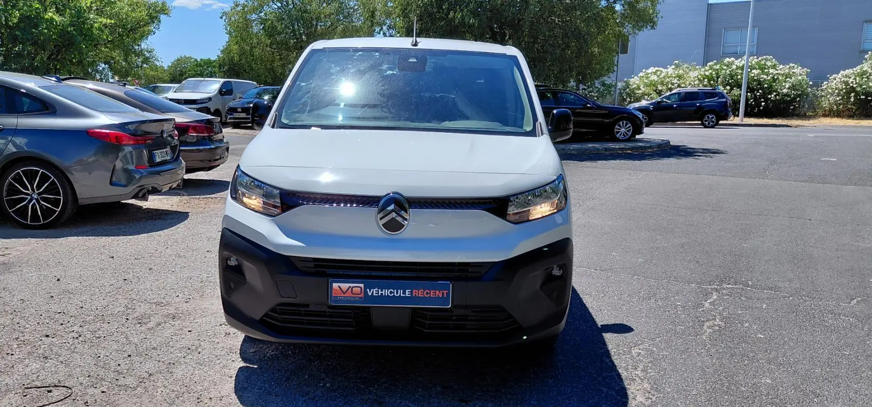 Vue avant d’un Citroën Berlingo blanc 2025 avec calandre noire et feux allumés, stationné en extérieur.