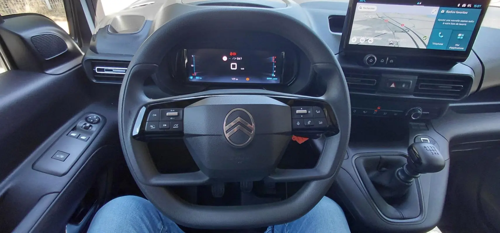 Vue intérieure centrée sur le volant multifonctions et le tableau de bord numérique du Citroën Berlingo blanc 2025.