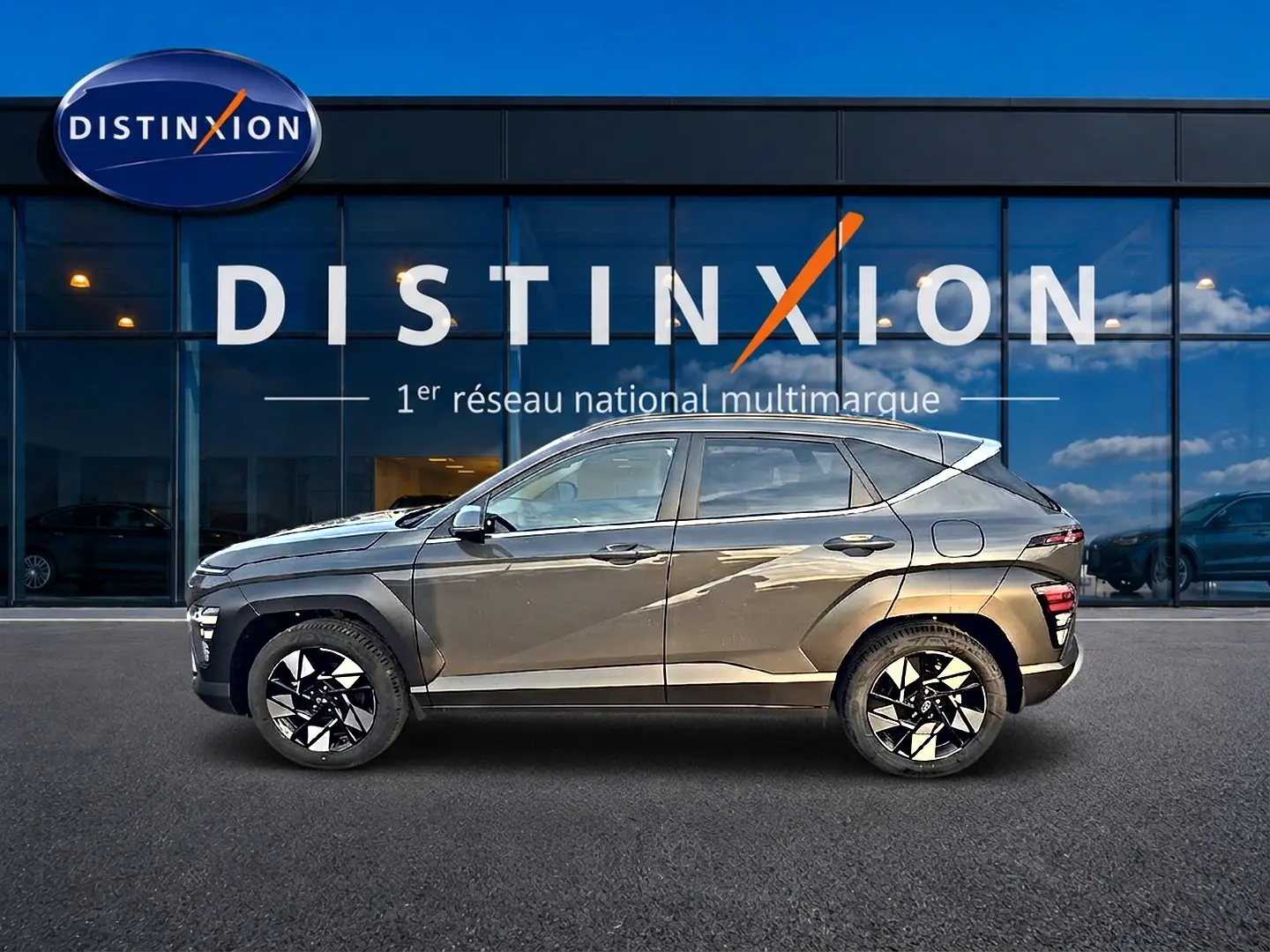 Vue de profil côté gauche d'une Hyundai Kona gris ecotronic avec jantes alliage noires et blanches, devant une vitrine Distinxion.