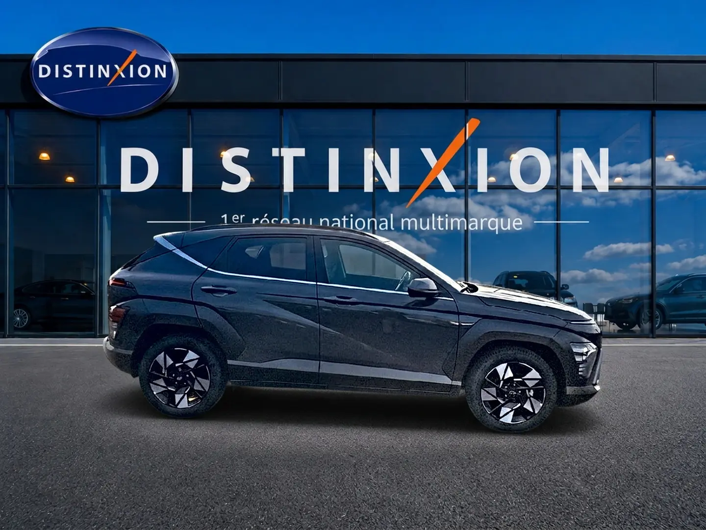 Profil droit du Hyundai Kona 2025 gris ecotronic avec jantes alliage noires et design moderne devant une vitrine Distinxion.