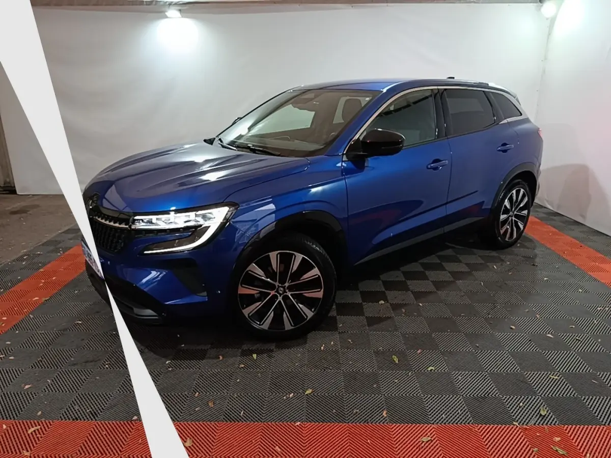 Renault Austral Techno bleu en 3/4 avant droit, avec jantes alliage et phares LED allumés dans un studio.