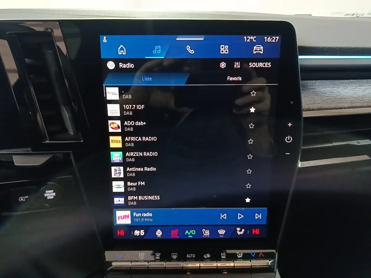 Gros plan sur l’écran tactile central du tableau de bord du Renault Austral bleu, affichant les stations radio numériques.