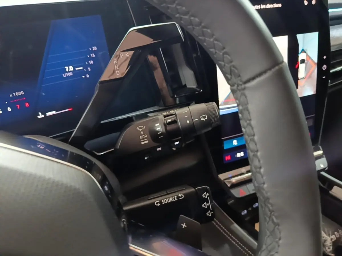 Gros plan intérieur sur le volant cuir noir et le combiné d'instruments numérique du Renault Austral bleu 2024.