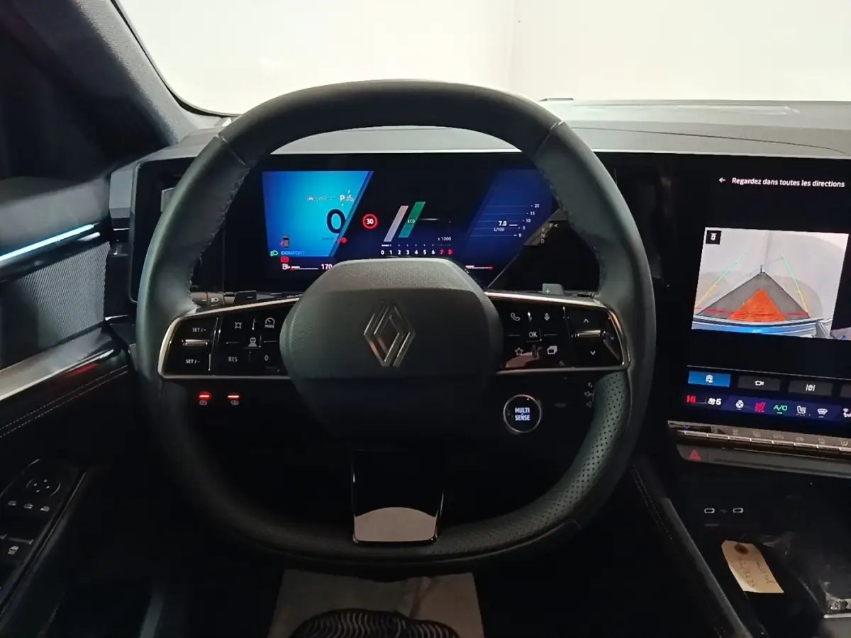 Vue intérieure centrée sur le volant cuir multifonctions et les écrans digitaux du tableau de bord du Renault Austral 2024.