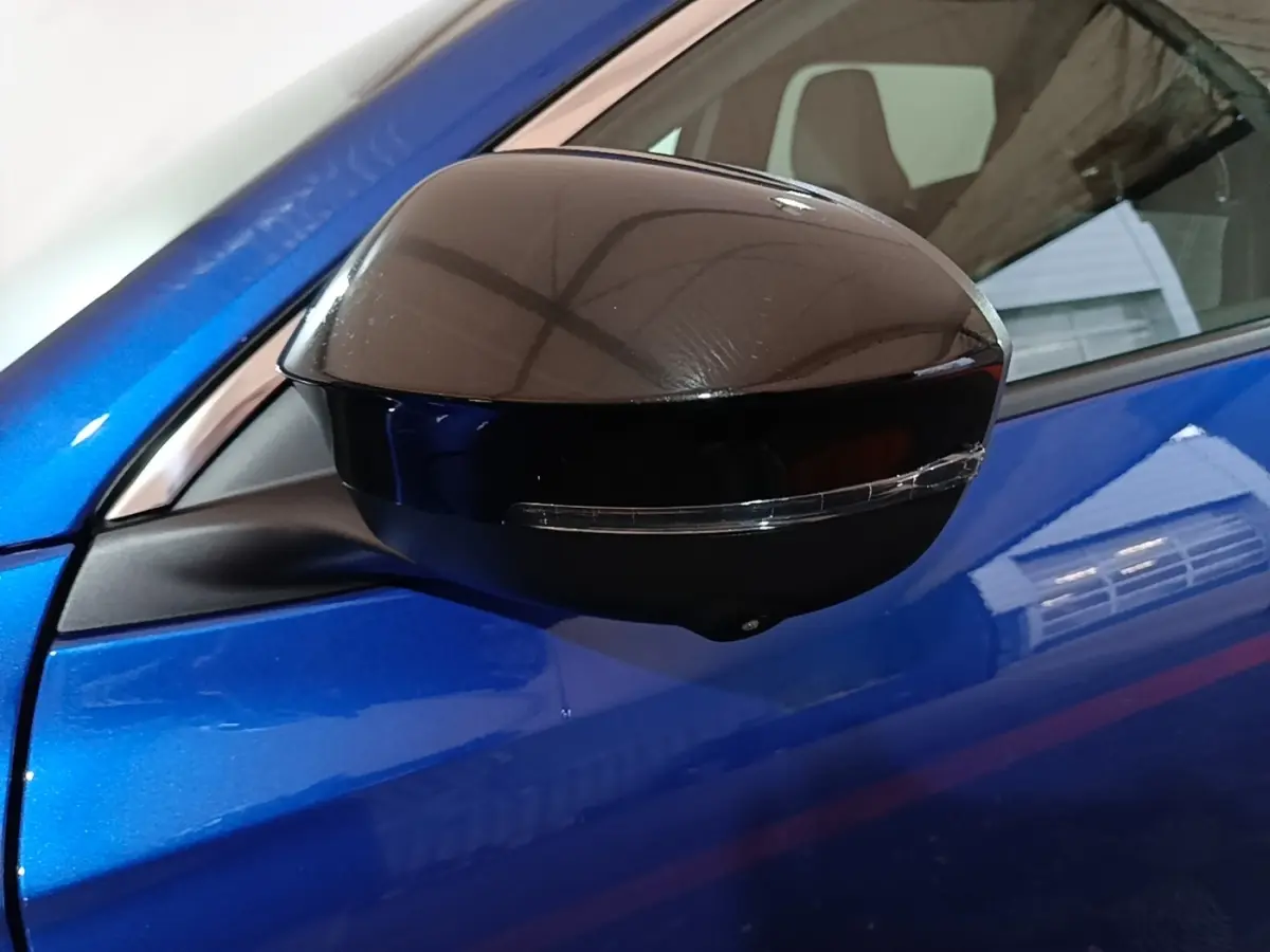 Rétroviseur droit noir brillant avec clignotant intégré sur Renault Austral bleu électrique, vue rapprochée côté conducteur.